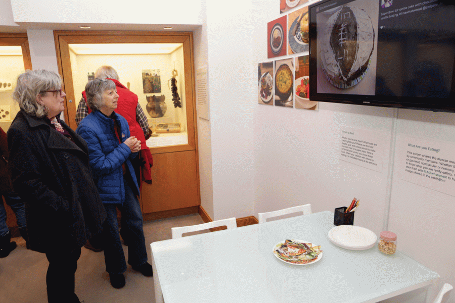 Viewers examine a detailed exhibit on the culture of food and the way humans interact with it.