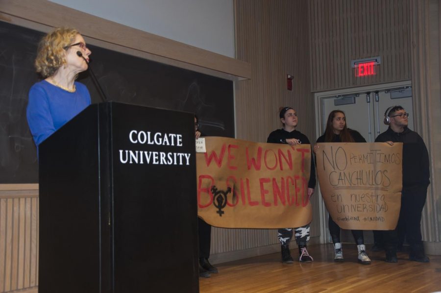Conservative author and commentator Heather Mac Donald in front of protesters at her lecture. These two signs were one of about six large signs that went up in the crowd during the Q&A section of the lecture, along with smaller posters. 