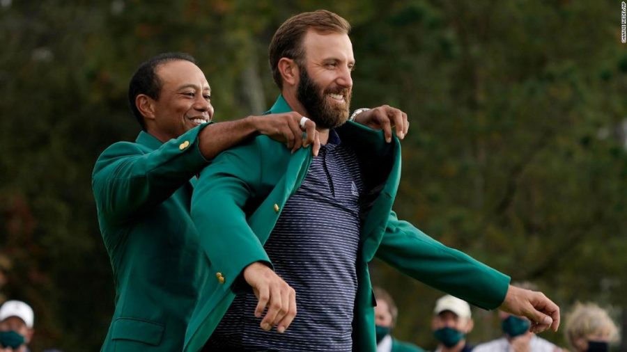 Tiger Woods helps Masters champion Dustin Johnson with his green jacket after his victory at the Masters golf tournament Sunday, Nov. 15, 2020, in Augusta, Ga. (AP Photo/Charlie Riedel)